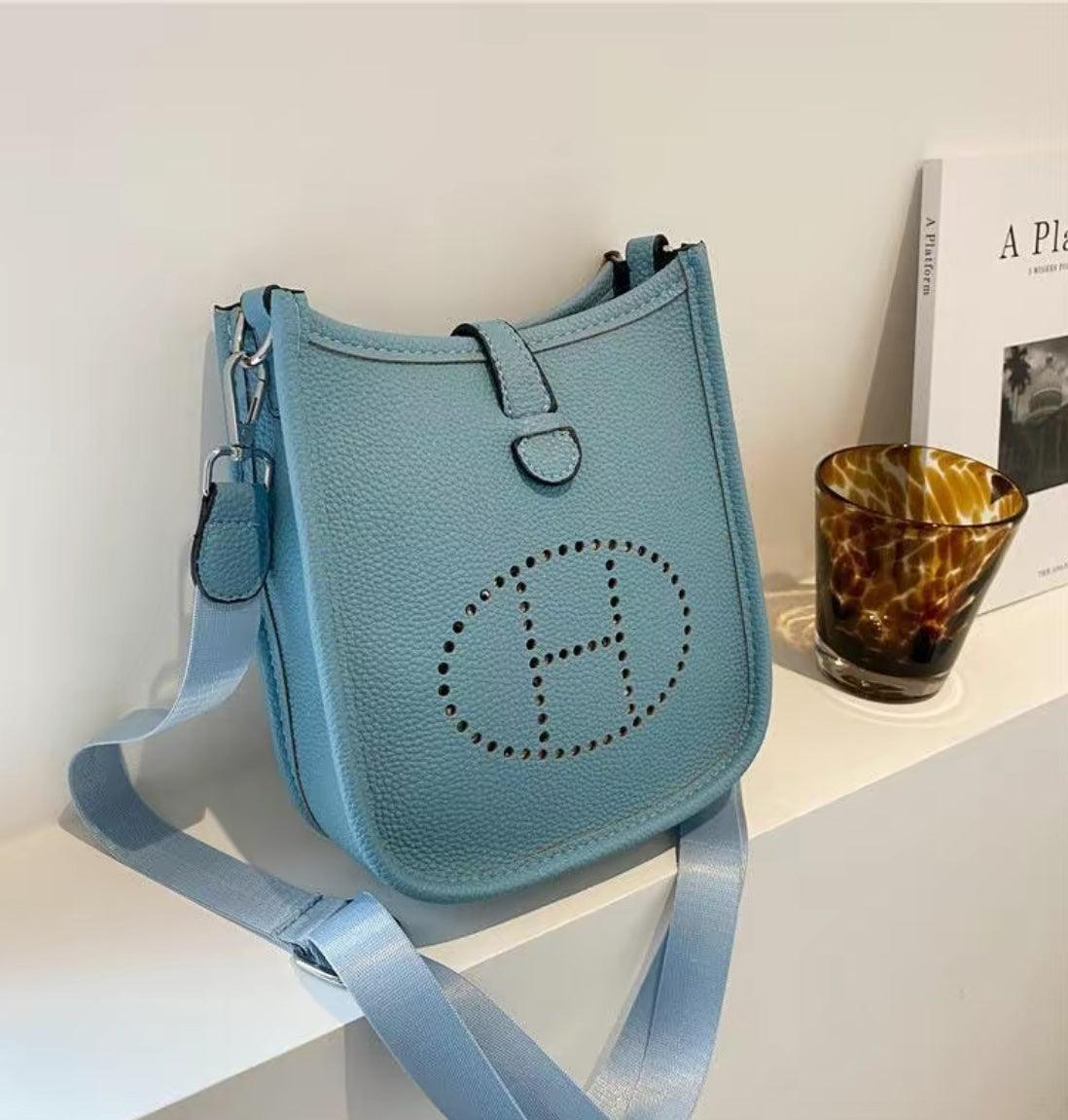 Leather crossbody with hole poke H logo.