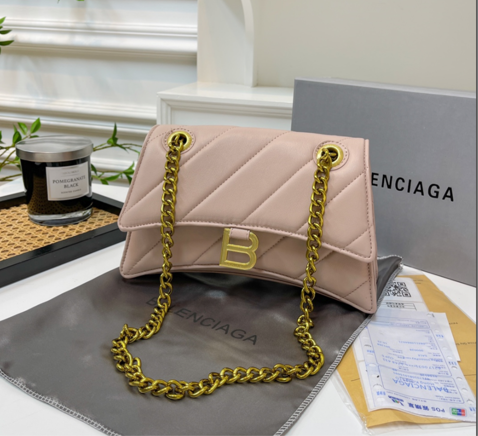 Large Solid light baby pink leather hourglass style B handbag with diagonal lines design. Crossbody bag with gold hardware, gold chain and gold letter B logo on the front.