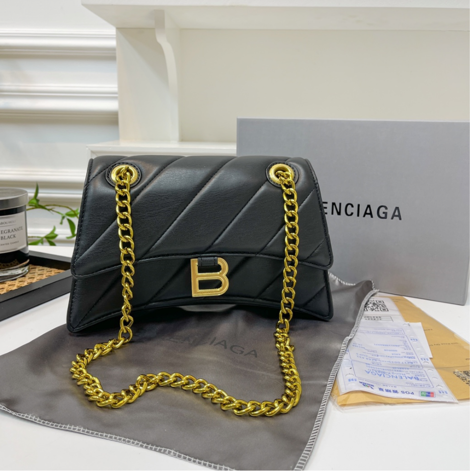 Solid black (large) leather hourglass B handbag with diagonal line design, gold chain, & B logo.