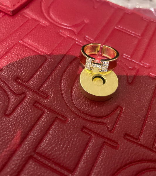 The metal color is gold with a thick red band and crystal H in the middle.