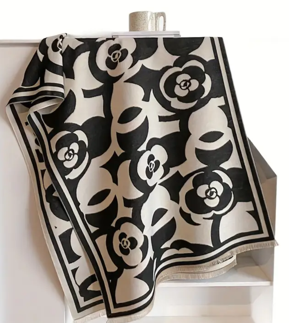 Black and white floral patterned scarf on a white stand with a black background. Cc style pattern