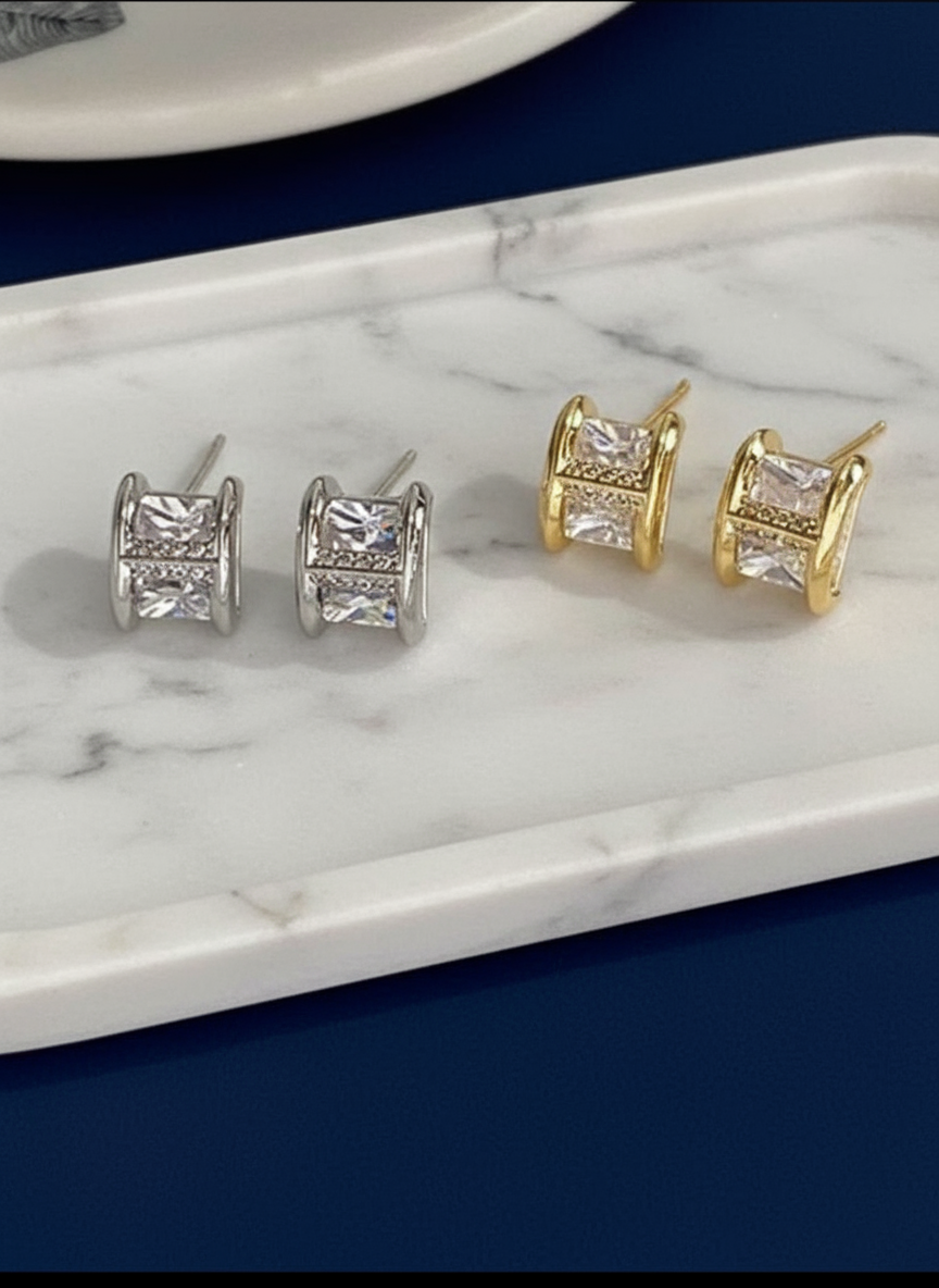 Pair of gold and silver square stud earrings on a blue background