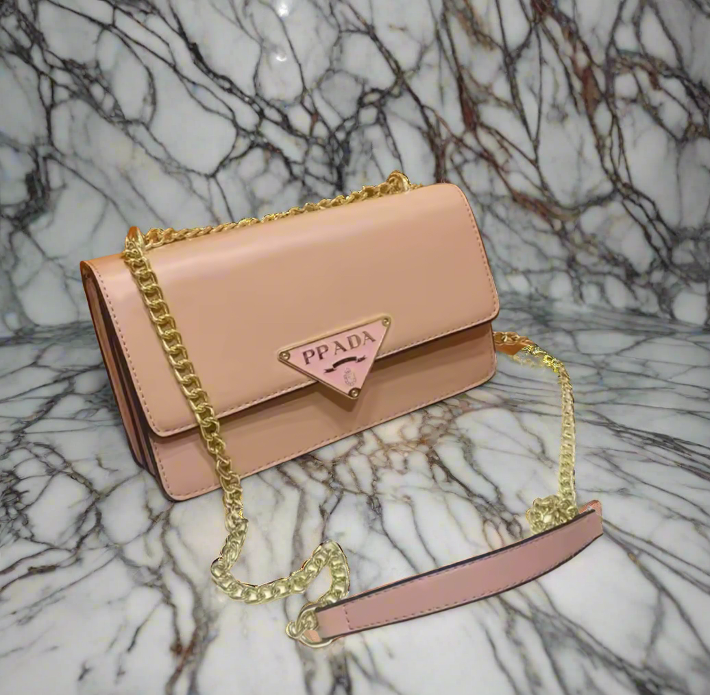 Pink handbag with gold chain on a marble background
