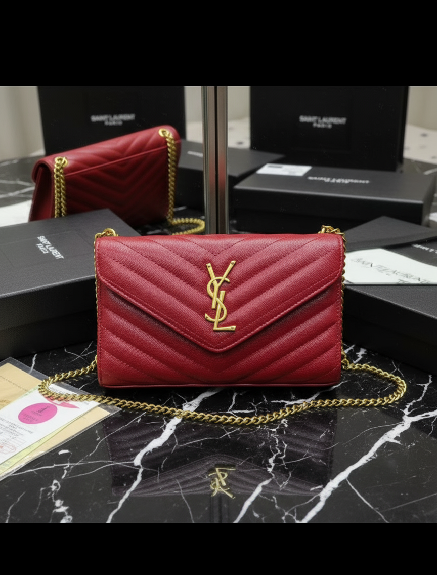 Red YSL handbag on a patterned surface with brand packaging in the background