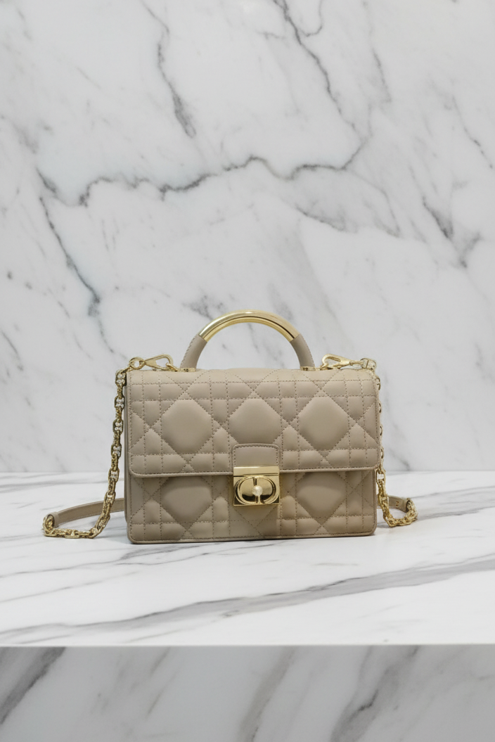 Beige handbag with gold accents on a light background