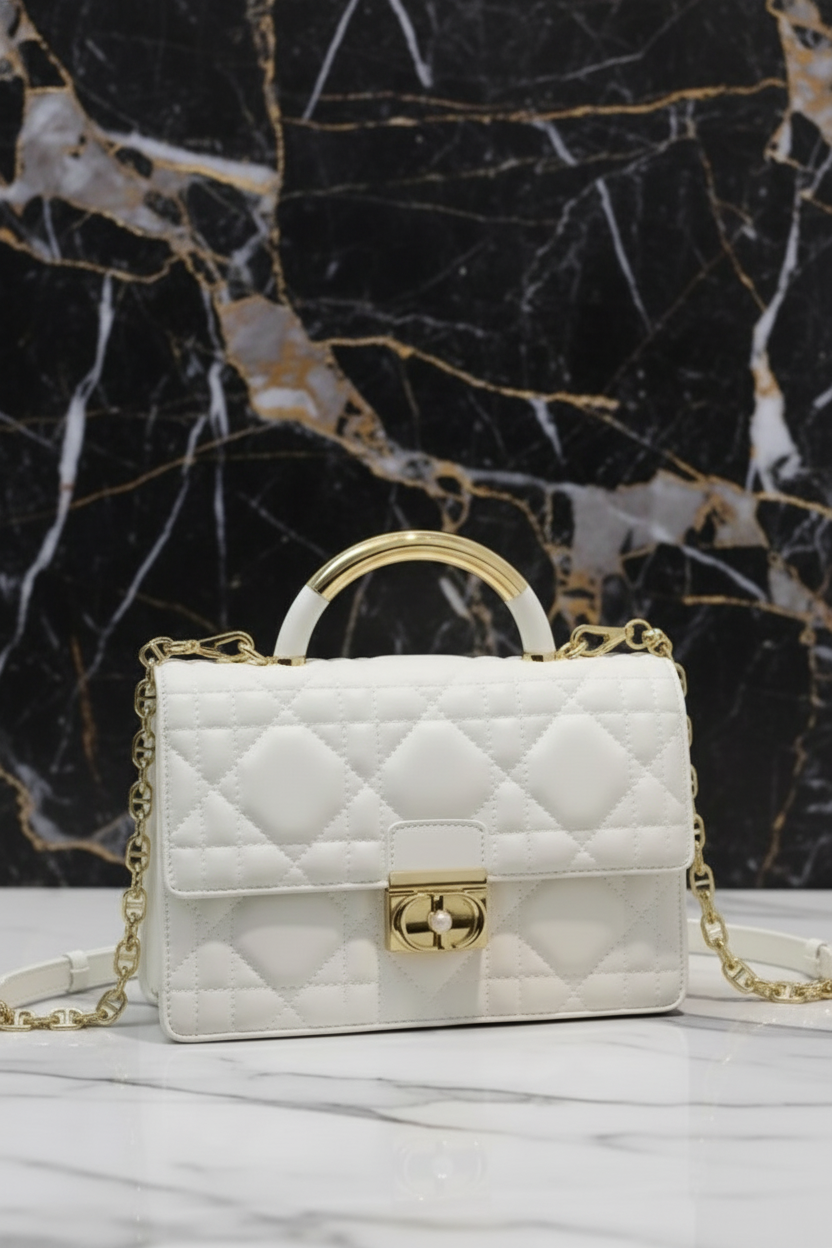 White quilted handbag with gold chain and handle on a white background