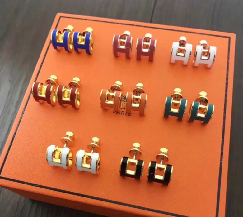 Set of earrings on an orange display box with visible brand name.