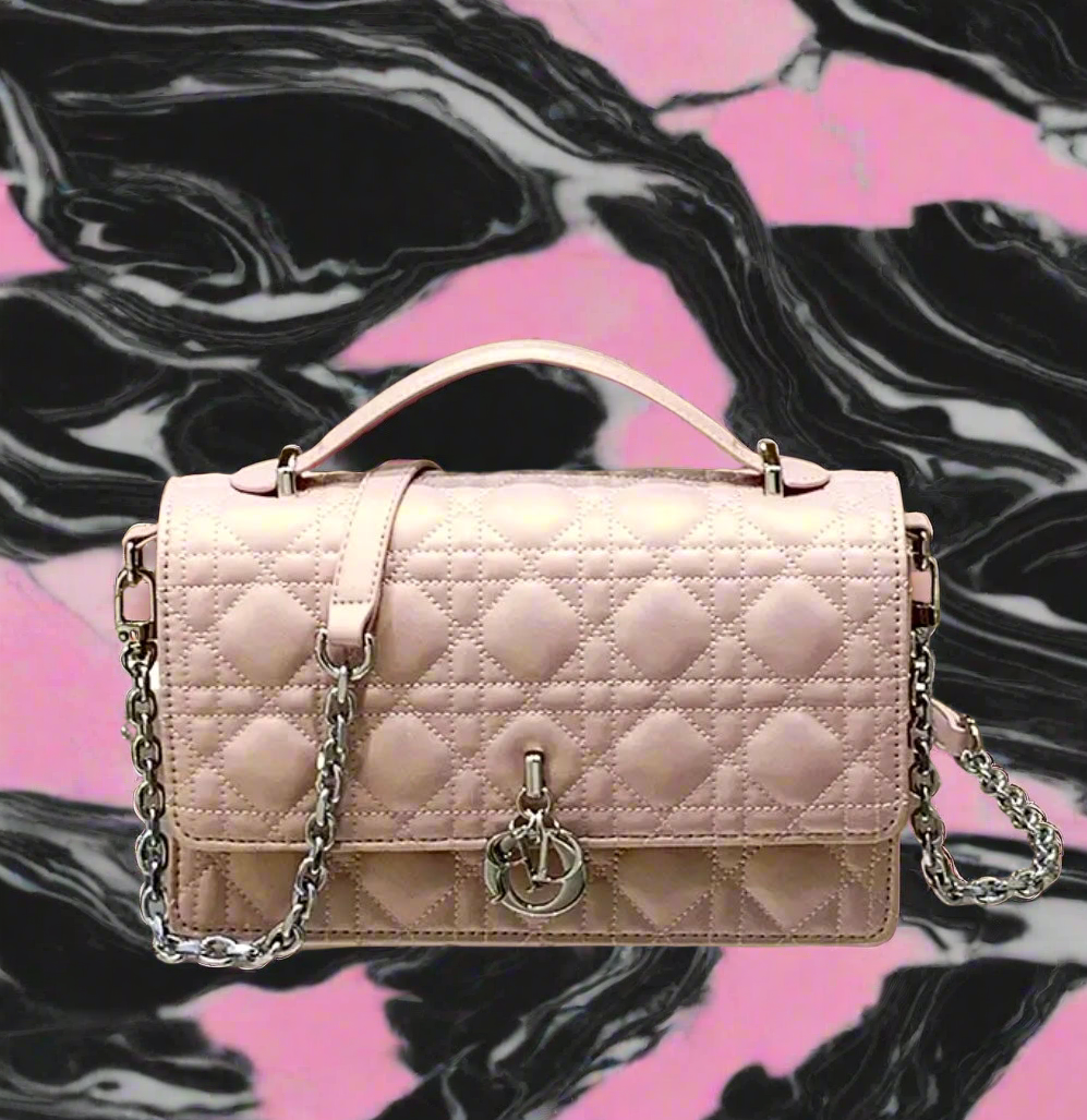 Shiny light pink CD crossbody bag with top handle and silver chain + hardware.  There are silver charms on the front.  (Not MATTE) 