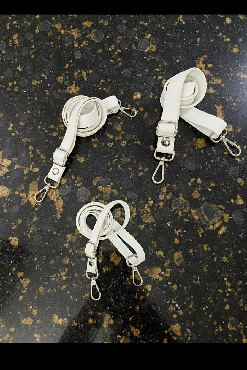 Three white straps with metal clasps on a gray background